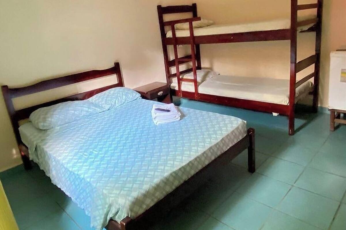 A room with two wooden bunk beds, one lower and one upper, with a ceiling fan above.