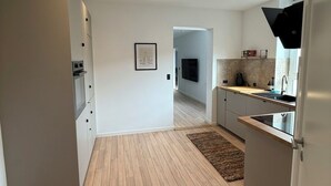 Una cuina moderna amb terra de fusta, armaris blancs i il·luminació encastrada.