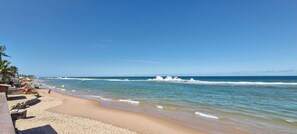 A beach with clear skies, calm waves, and a few people.