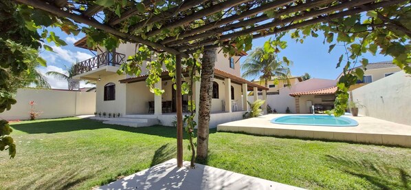A residential property with a swimming pool, a covered patio, and a well-maintained lawn.