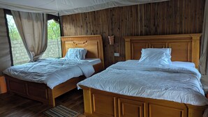Une pièce avec deux lits en bois, un plancher en bois, une fenêtre avec des rideaux et un lambris en bois.
