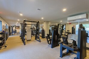 Ein Fitnessstudio mit verschiedenen Trainingsgeräten, Spiegeln und freiem Blick ins Freie.