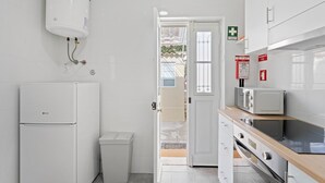 A compact kitchen with a built-in refrigerator, a microwave, and a trash bin. - GuestReady - Rosemary's lovely home with a garden (Porto)