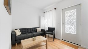 A modern living room with a sofa, a chair, a coffee table, and a door with a decorative glass panel. - GuestReady - Rosemary's lovely home with a garden (Porto)