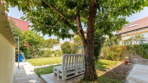 A wooden bench under a tree in a residential backyard. - GuestReady - Rosemary's lovely home with a garden (Porto)