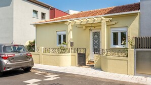 A two-story house with a tiled roof, a garage, and a car parked in front. - GuestReady - Rosemary's lovely home with a garden (Porto)
