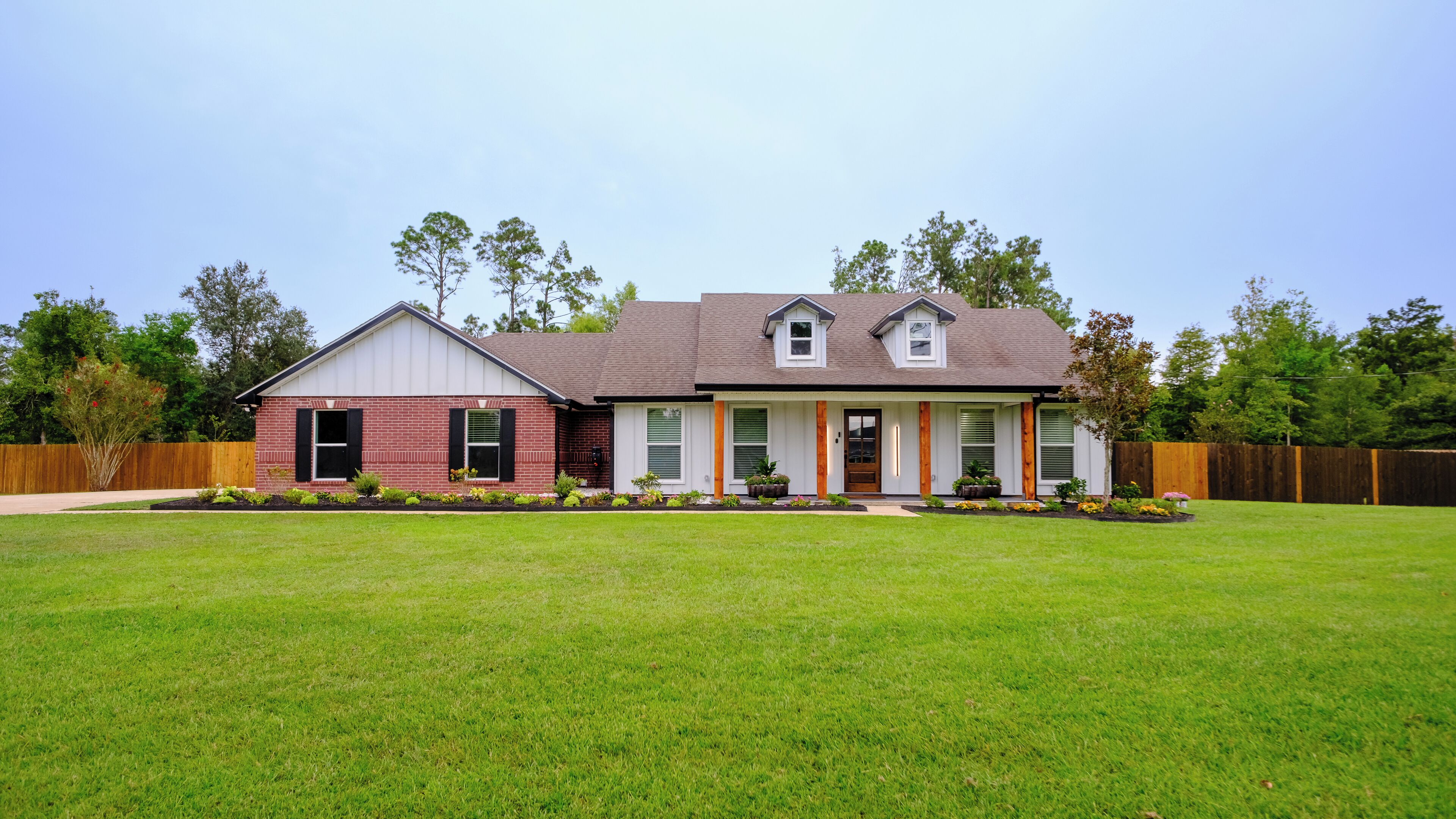 A two-story house with a brick exterior, a front porch, and a well-maintained lawn.