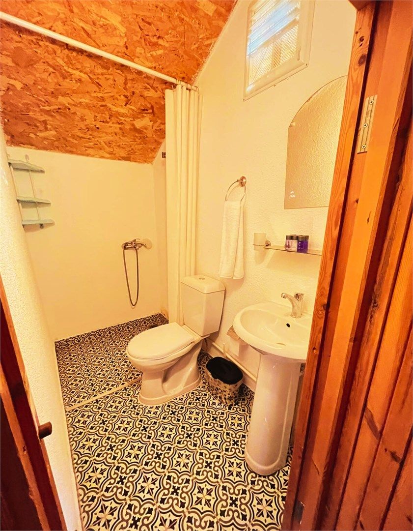A bathroom with a patterned floor, a toilet, a sink, and a shower area.