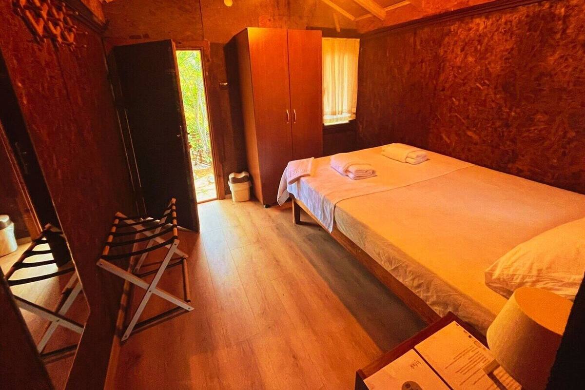 A cozy room with a wooden bed, a small table with a menu, and a window with curtains.