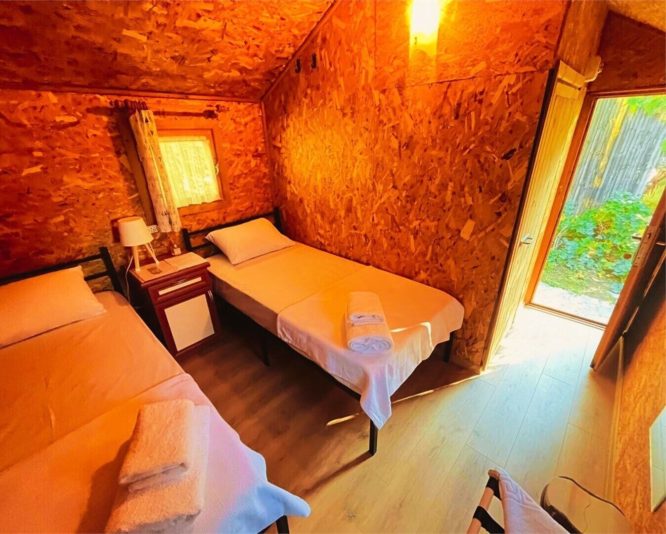 A cozy room with two beds, a small table, and a window.