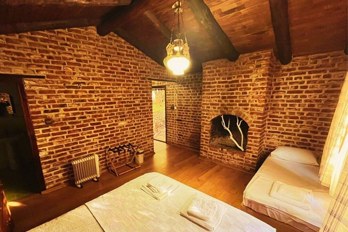 A rustic room with exposed brick walls, a fireplace, and a bed with white linens.