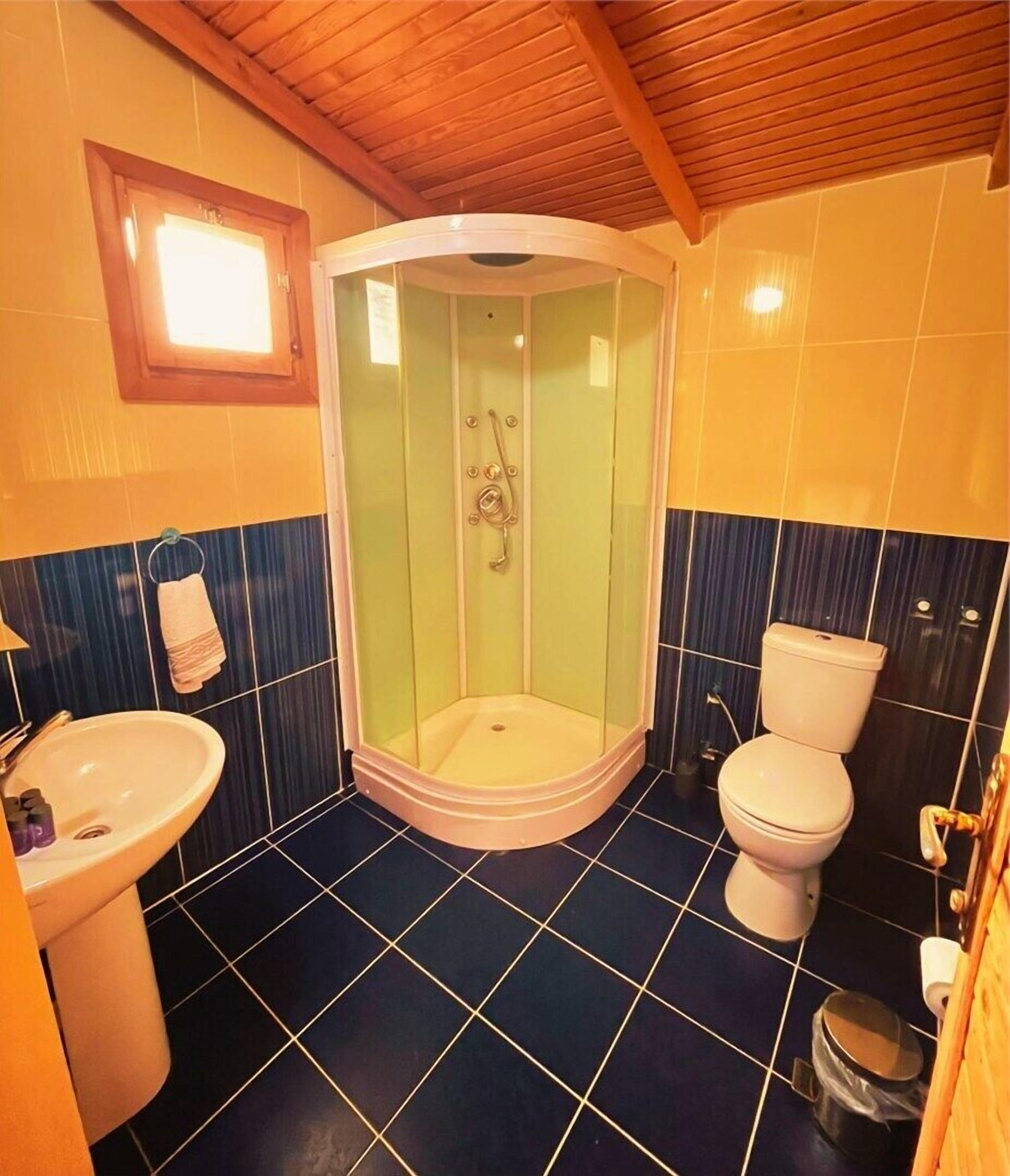 A bathroom with a corner shower, a sink, a toilet, and a window.