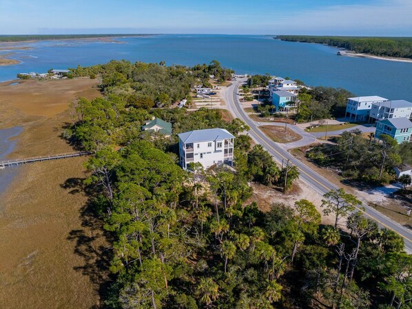 An aerial view of a coastal residential area with houses, a road, and a bridge over water. - Villa Laguna (Port St. Joe)