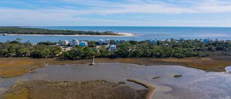 Vista aérea de una zona costera con playa, casas y un muelle.