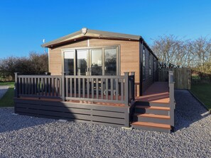 Une maison mobile moderne, de plain-pied, dotée d’une terrasse en bois et d’un petit porche.