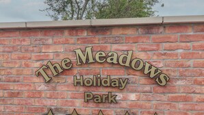 A brick wall with a sign that reads "The Meadows Holiday Park" and five stars below it. - Meadows Park 4 (Hull)