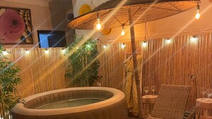 Un área de spa con una bañera de hidromasaje, sillones de descanso y una pared de bambú.