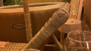 Una habitación con un rascador para gatos tejido, una mesita redonda con un vaso y una pared de bambú.