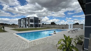 A modern two-story building with a swimming pool and lounge chairs. - Luxurious Motherland Apartments (Lusaka)