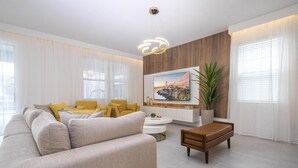 Ein modernes Wohnzimmer mit einem beigefarbenen Sofa, einem Holztisch und einem an der Wand befestigten Fernseher.