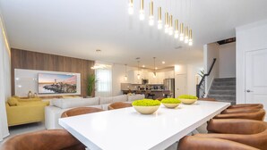 Eine moderne Küche mit Essbereich, einer Treppe und einem Wohnzimmer mit Sofa und Fernseher.