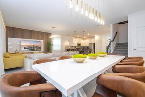 Une cuisine moderne avec un coin repas, un escalier et un salon doté d’un canapé et d’une télévision.