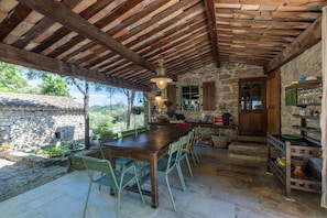 A rustic stone building with a wooden table and chairs, a stone wall, and a wooden door.