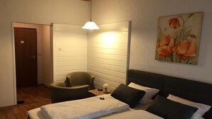 Une chambre à coucher avec un lit, une chaise, un bureau et un tableau accroché au mur.