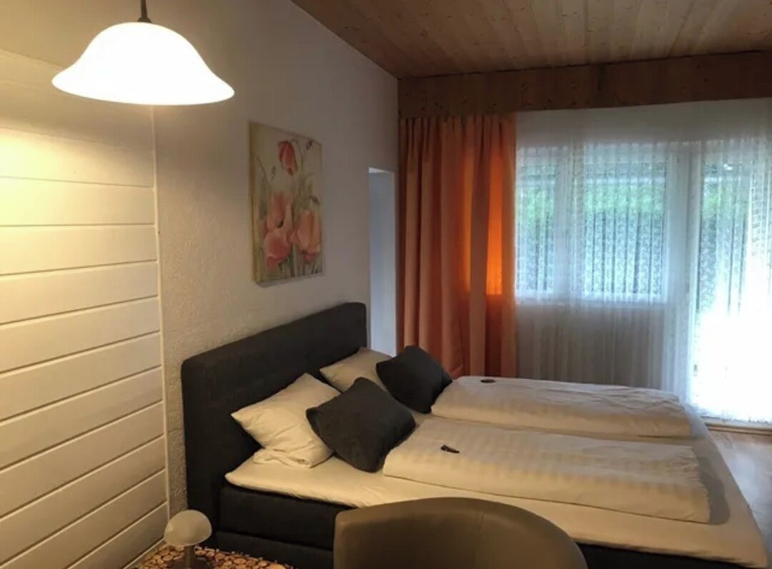 Una habitación con dos camas, un cuadro en la pared y una ventana con cortinas.