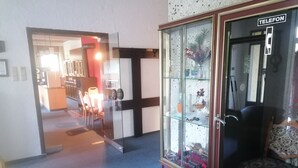Une pièce comprenant une vitrine contenant divers objets, un téléphone et une chaise à motifs.