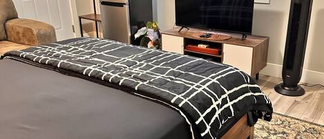 Un dormitorio con cama, televisión, calefactor y ventana con persianas.