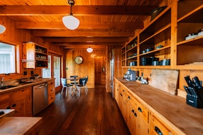 Un intérieur en bois comprenant une cuisine, un coin repas et une horloge au mur.