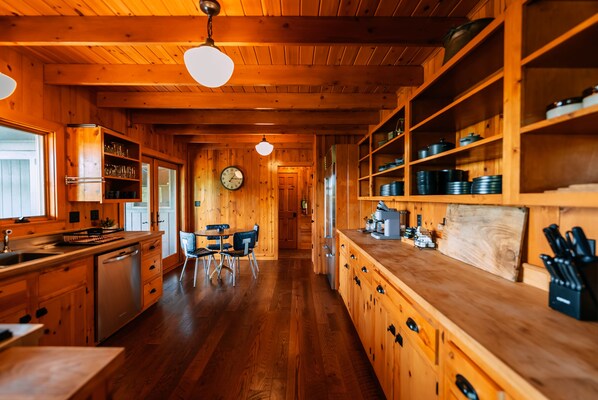 A wooden interior with a kitchen, dining area, and a clock on the wall.