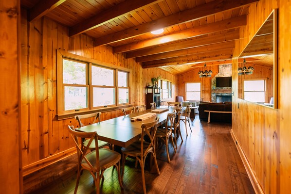 Un intérieur en bois avec une longue table à manger, des chaises et une cheminée en pierre.