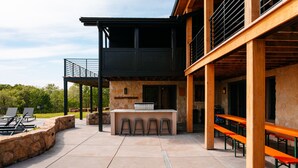 Uma área de estar ao ar livre com um muro de pedra, um balcão de bar e mesas e cadeiras externas.