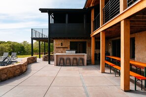An outdoor patio area with a stone wall, a bar counter, and outdoor seating.