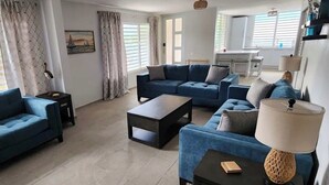 A modern living room with a blue sofa set, a coffee table, and a lamp. - Beachfront, Luxury Bungalow, Private Premium Pool! (Fortuna)