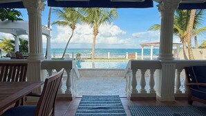 A covered outdoor seating area with a view of the ocean and palm trees. - Beachfront, Luxury Bungalow, Private Premium Pool! (Fortuna)