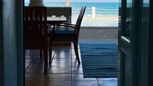 A view from a room to a beach with a palm tree, a chair, and a table. - Beachfront, Luxury Bungalow, Private Premium Pool! (Fortuna)