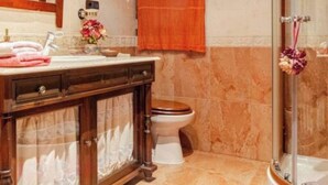 Et badeværelse med vaskebord, toilet og brusebad.