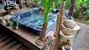 Een hottub omringd door tropische planten en houten decoratie.