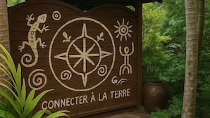 Een houten bord met een kompas en de tekst 'CONNECTER À LA TERRE', omringd door natuur.