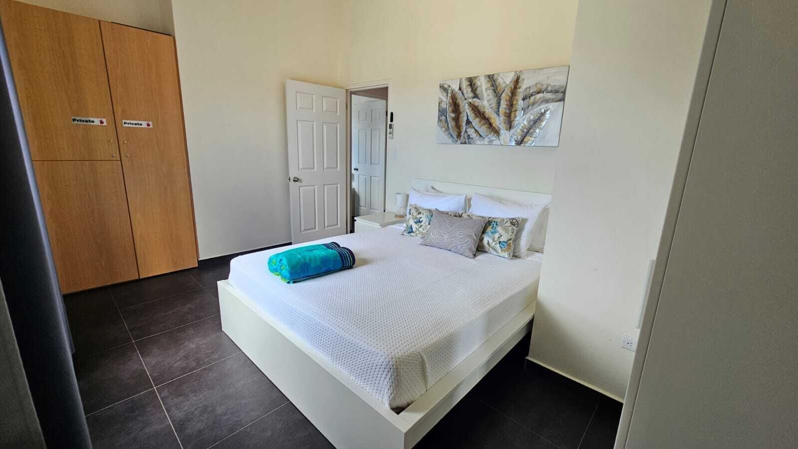 A bedroom with a bed, a door, and a wall-mounted artwork.