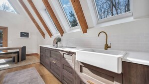 A modern kitchen with a large white sink, wooden cabinets, and a skylight.