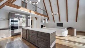A modern kitchen with built-in appliances, a large island, and a loft bedroom with a balcony.