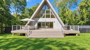 A modern, triangular-shaped building with a deck, outdoor seating, and a large umbrella.