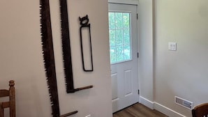Ein Zimmer mit Holzboden, einer weißen Tür und einem Fenster mit Blick auf Grünfläche.
