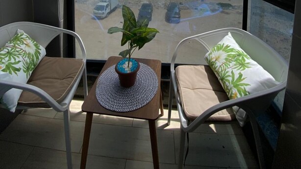 Un balcón con dos sillas, una mesita con una planta y vista a la playa y al océano.