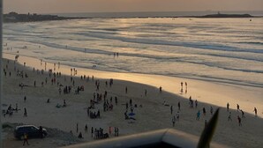 Una playa con gente y un atardecer.