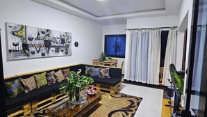 Un salón moderno con un sofá negro, una mesa de centro y un cuadro abstracto grande en la pared.